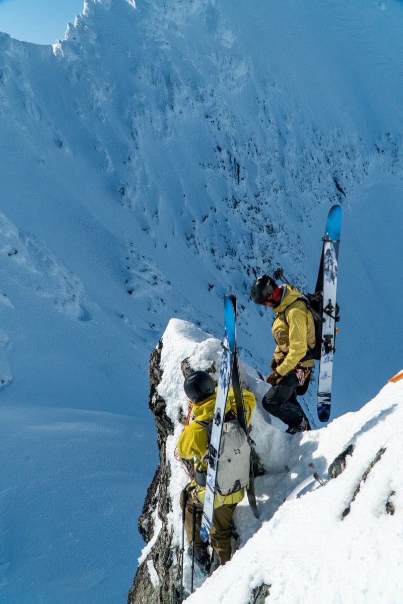 Two skiers carrying SGN Tunnelvisjon skis up a steep ridge